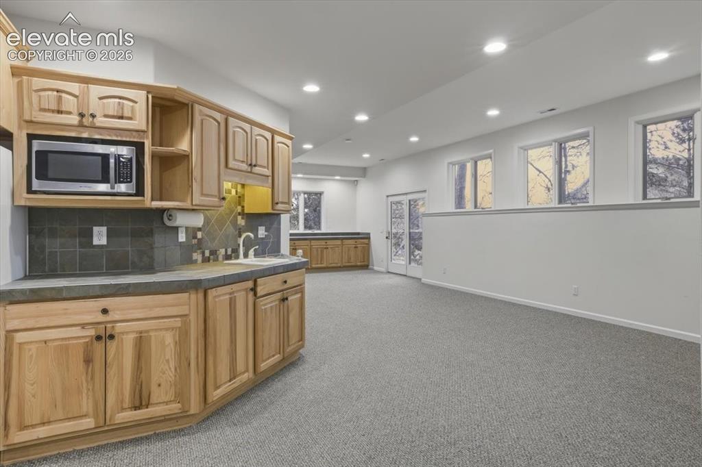 Image 35 of 48: Recessed lighting, wood cabinetry, built-in microwave, tile backsplash.