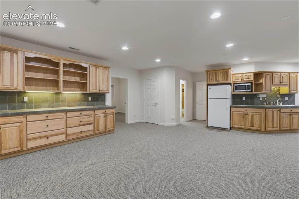 Image 37 of 48: Recessed lighting illuminates extensive wood cabinetry with shelving and a