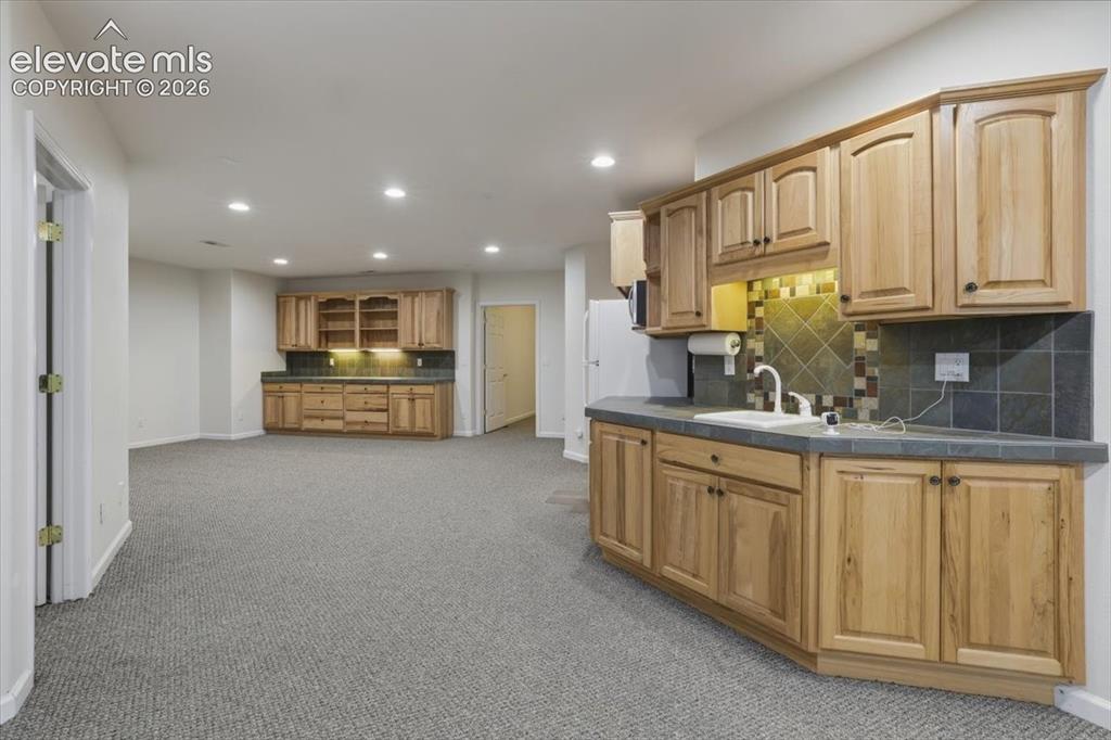 Image 38 of 48: Spacious room featuring light-toned wood cabinetry, built-in sink, tiled ba
