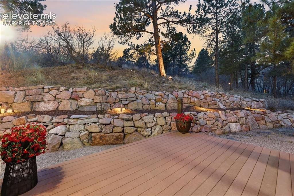 Image 48 of 48: Spacious composite deck with integrated lighting, tiered stone retaining wa
