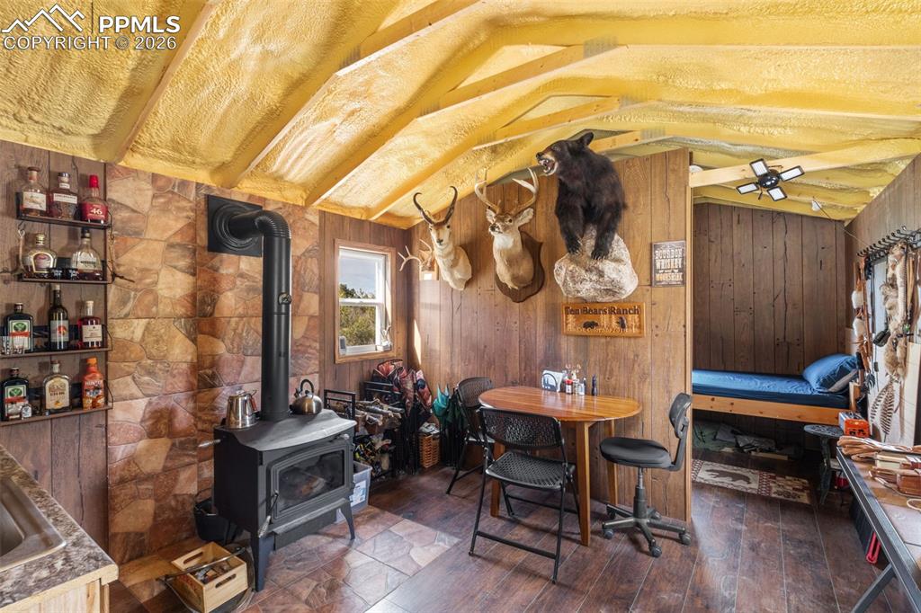 Image 38 of 50: Saloon cabin kitchen and dining area with wood stove.