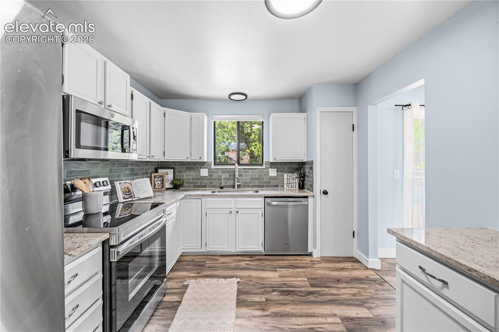 Image 8 of 32: bright white cabinets and pantry to the right of the dishwasher