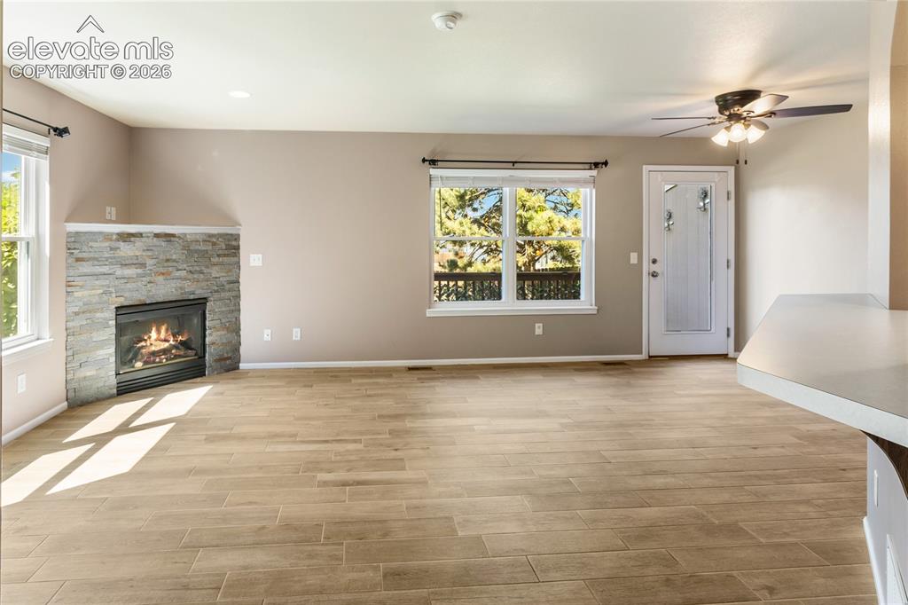 Image 13 of 48: New floors and stacked stone on fireplace. Walks out to back deck.