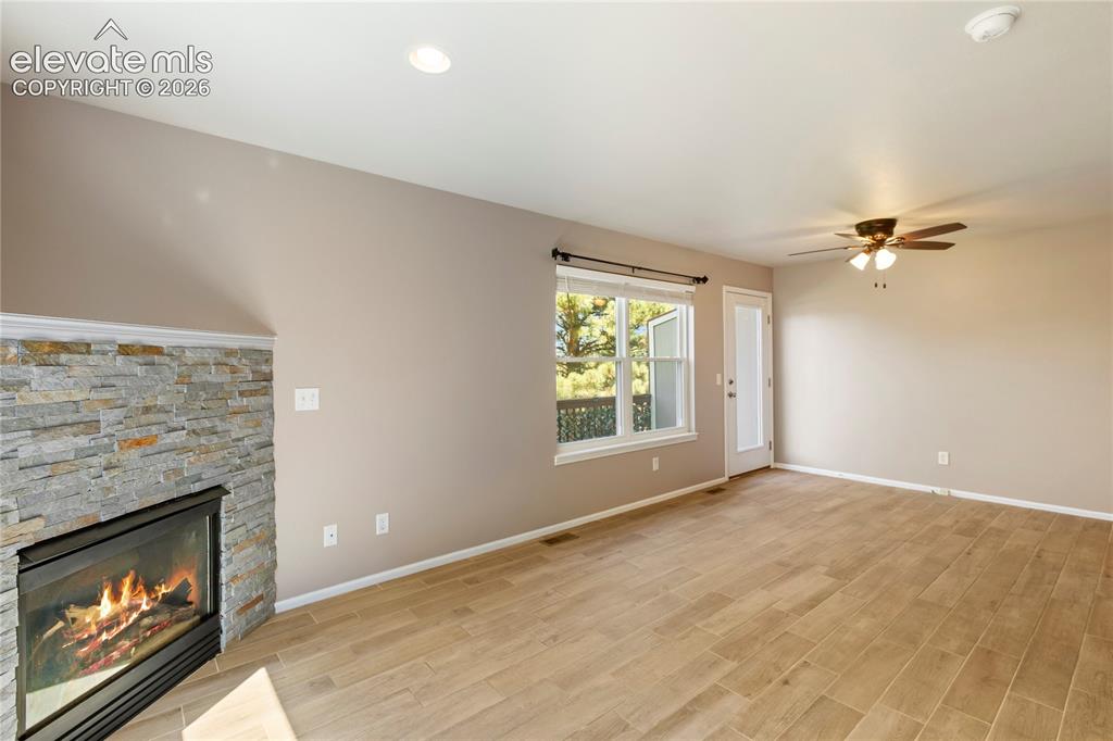 Image 14 of 48: New floors and stacked stone on fireplace. Walks out to back deck.