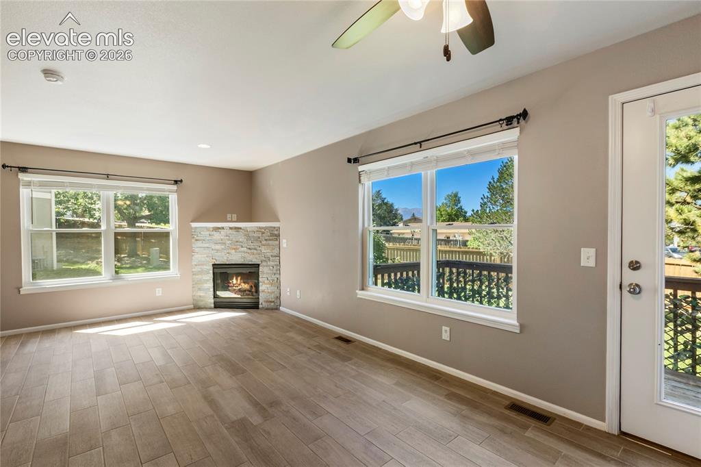Image 18 of 48: New floors and stacked stone on fireplace. Walks out to back deck.