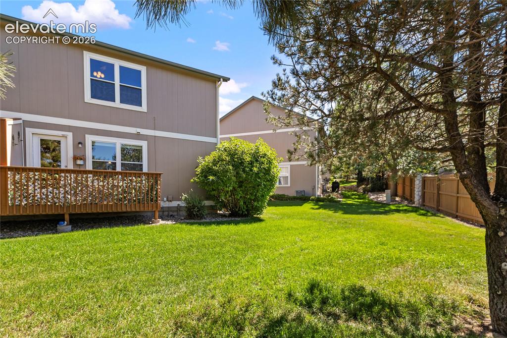 Image 45 of 48: Back yard has open grass area and deck.