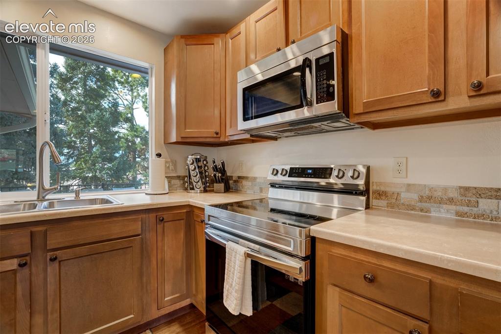 Image 11 of 50: Wood-finish cabinetry paired with light-toned countertops and a stone-look 