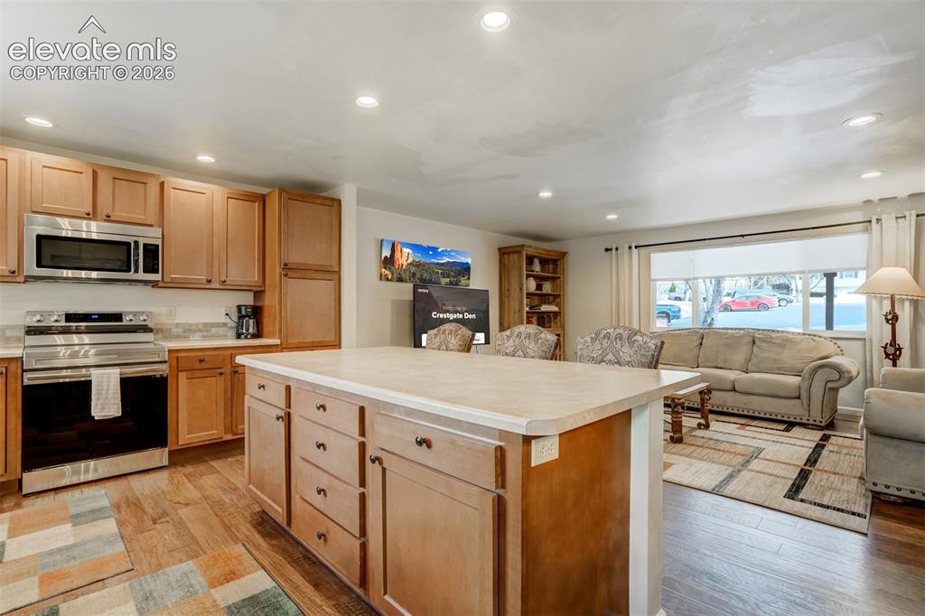 Image 12 of 50: Hardwood-finish flooring throughout, recessed lighting, and a kitchen islan
