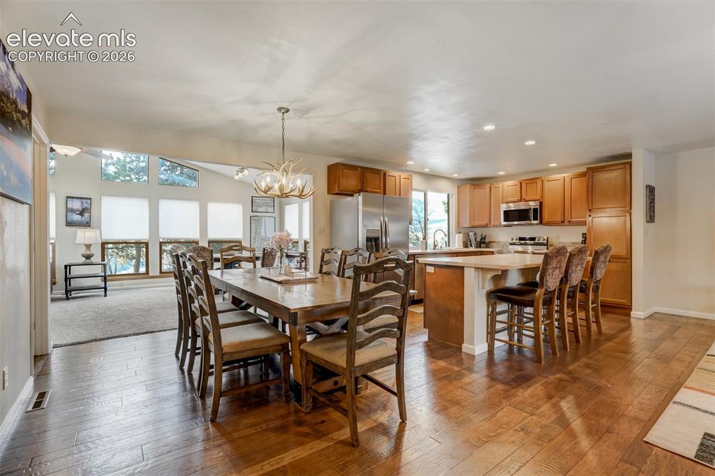 Image 13 of 50: Expansive wood-finish flooring throughout the dining area and kitchen