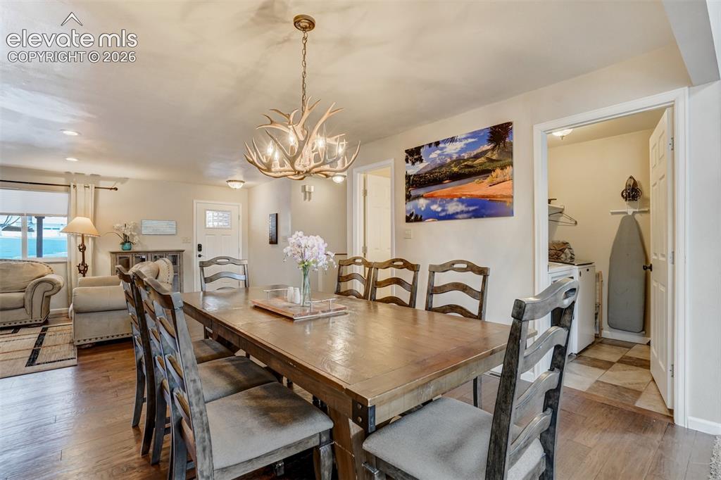 Image 14 of 50: Wood-finish flooring throughout, featuring a distinctive antler-style chand