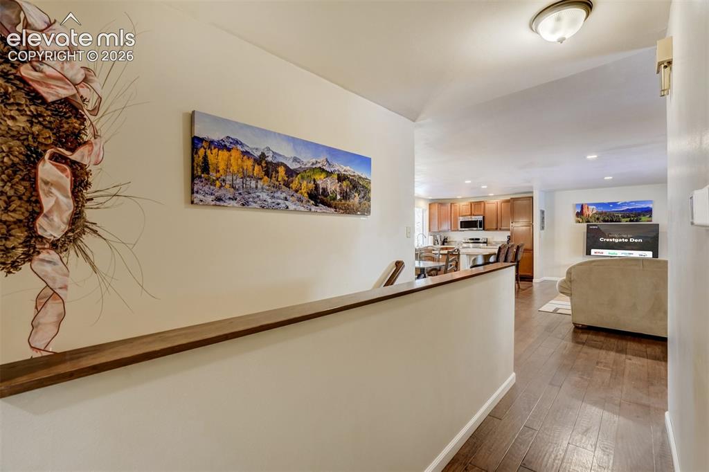 Image 22 of 50: Wood-finish flooring throughout, with a wood-top half-wall