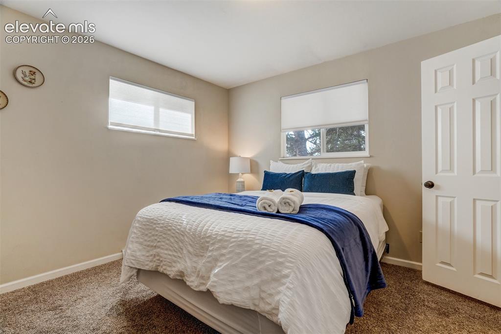 Image 27 of 50: Neutral wall tones, carpeted flooring, window with roller shade, and panele