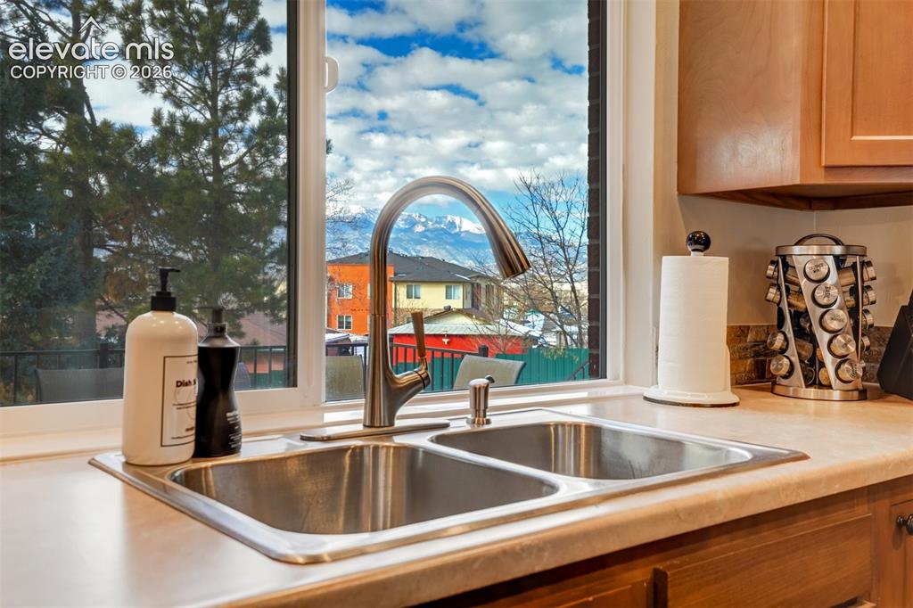 Image 3 of 50: Dual basin stainless steel sink with a high-arc faucet, set within a light-