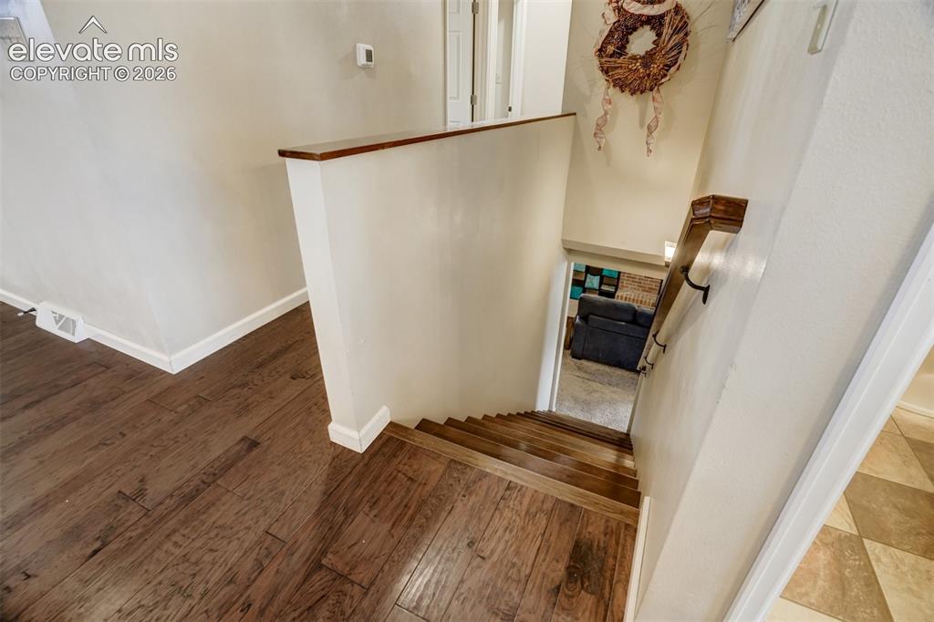 Image 33 of 50: Wood-finish flooring throughout, featuring a wood handrail with dark metal