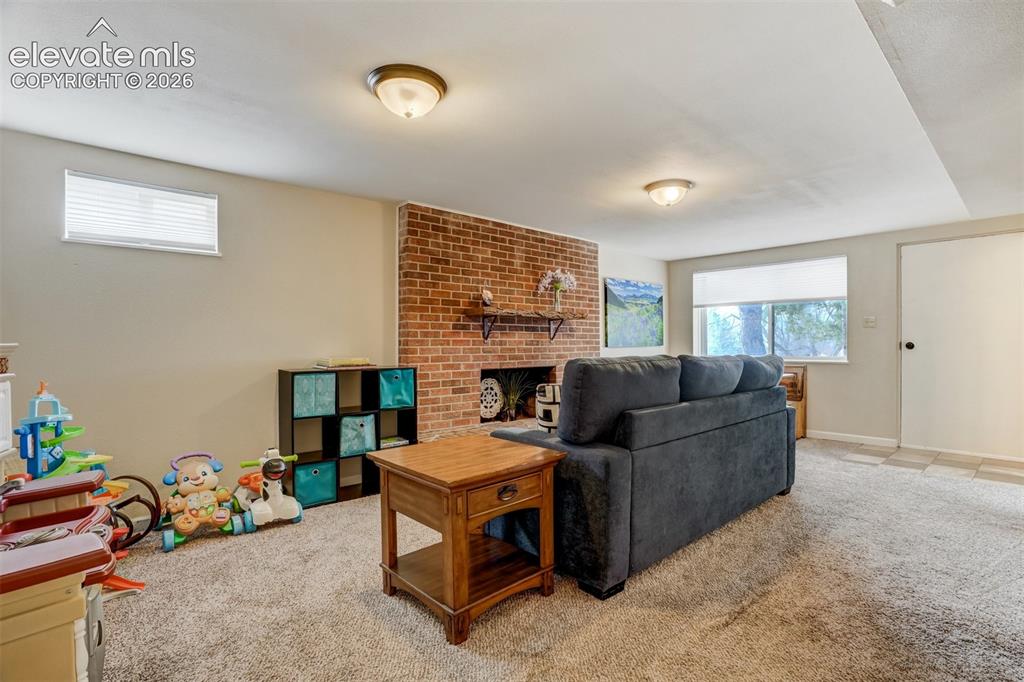 Image 34 of 50: Brick accent wall with a built-in shelf, recessed lighting, and carpeting t