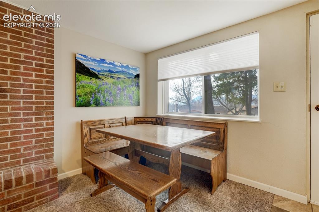 Image 37 of 50: Built-in banquette seating, a large window, and brick detailing