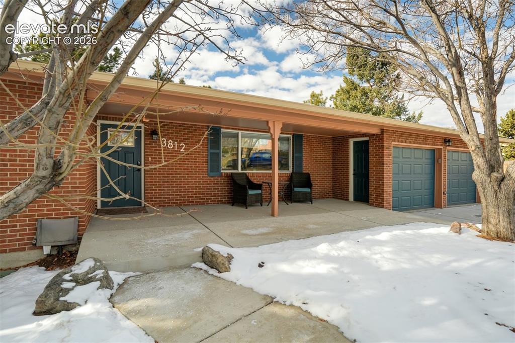 Image 4 of 50: Brick exterior with a covered porch, two-car garage, and concrete walkway