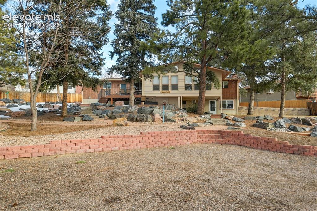 Image 46 of 50: Expansive yard featuring a terraced retaining wall, mature trees, and natur