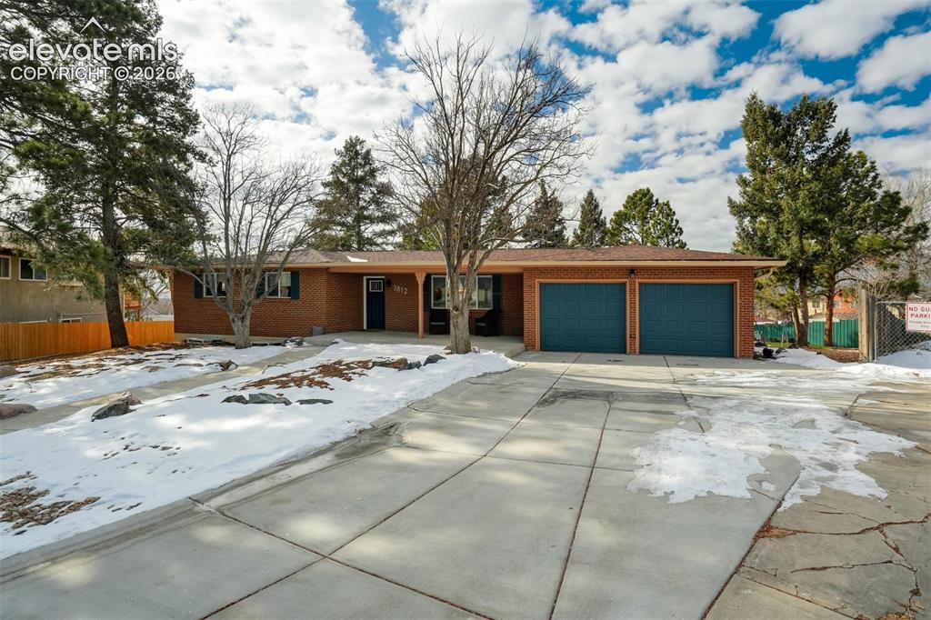Image 48 of 50: Brick exterior with a prominent two-car attached garage, featuring a concre