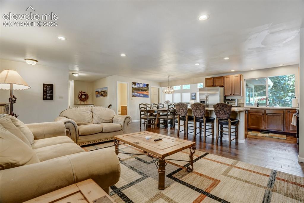 Image 8 of 50: Open-concept living space featuring wood-finish flooring, recessed lighting