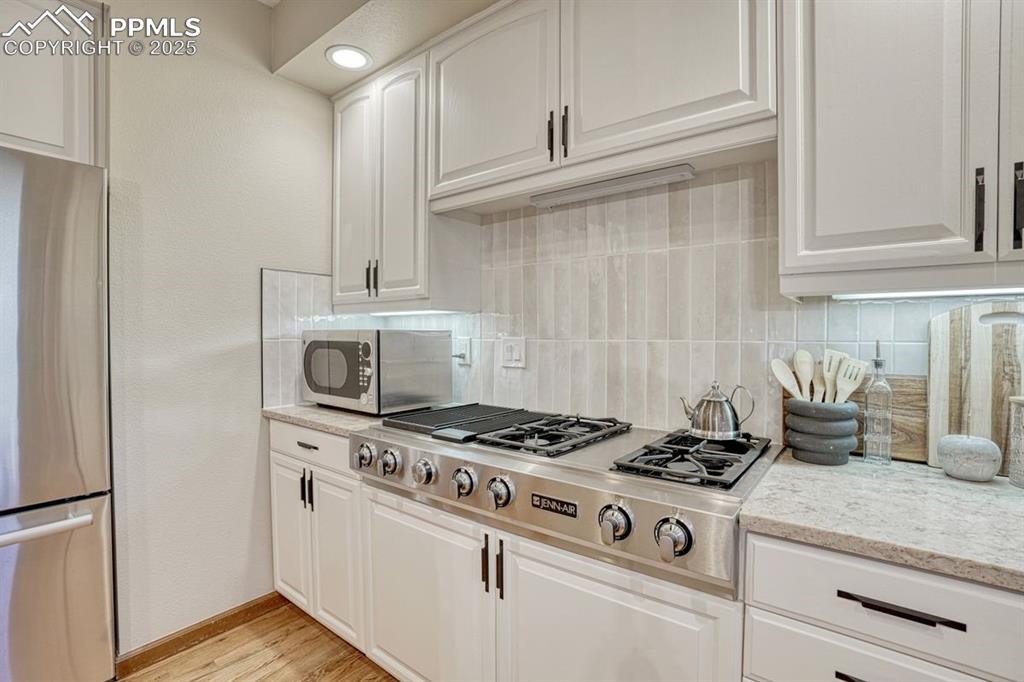 Image 17 of 43: Extended decorative tile & sleek countertops surround the six-burner Jenn-A