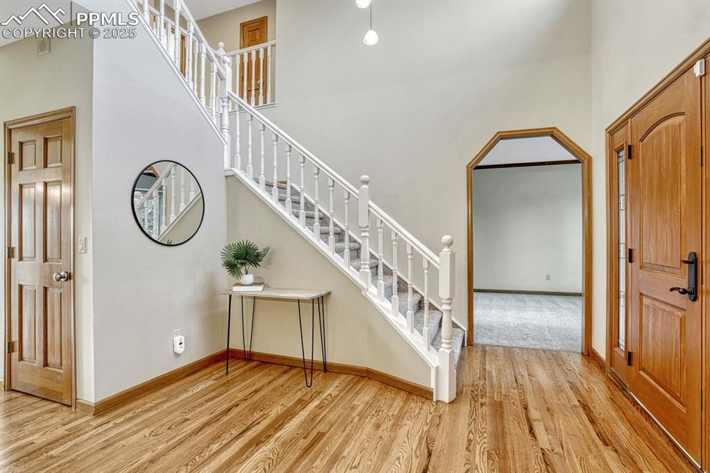 Image 8 of 43: The bright foyer has refinished hardwood floors & dramatic new lighting