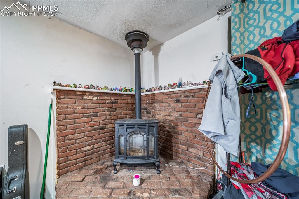Image 30 of 45: Unit 3 Bedroom with a wood stove and a textured ceiling