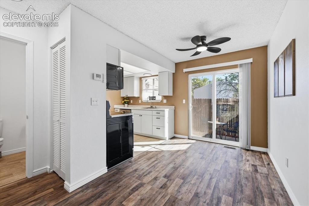 Image 10 of 27: Wood-finish flooring, white walls, and a sliding glass door to the patio
