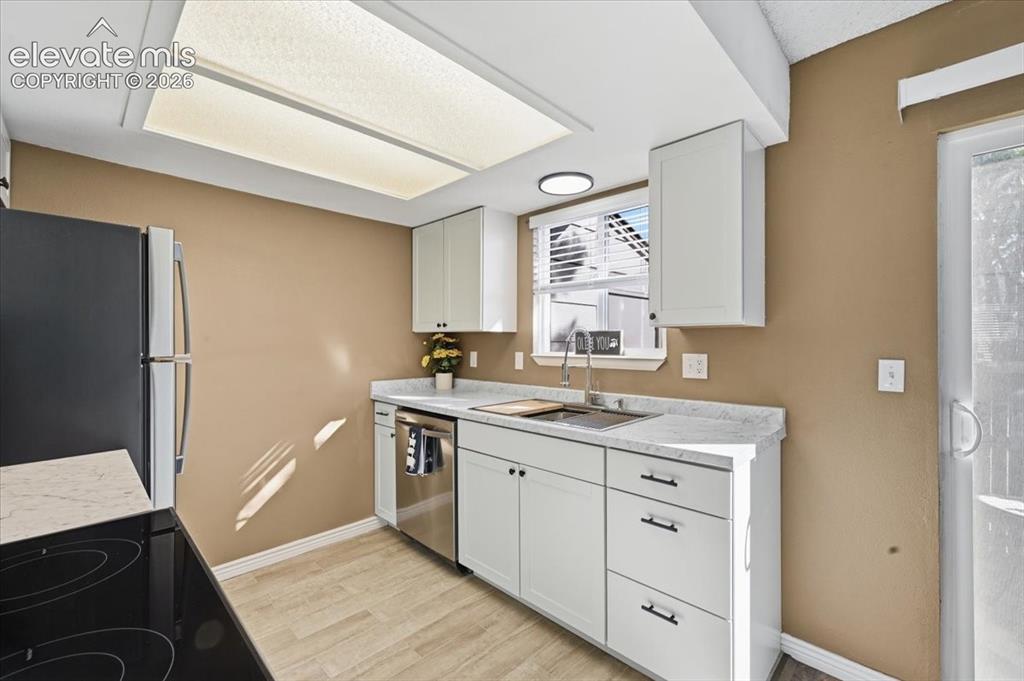Image 11 of 27: Kitchen featuring white cabinetry, light countertops, wood-finish flooring,