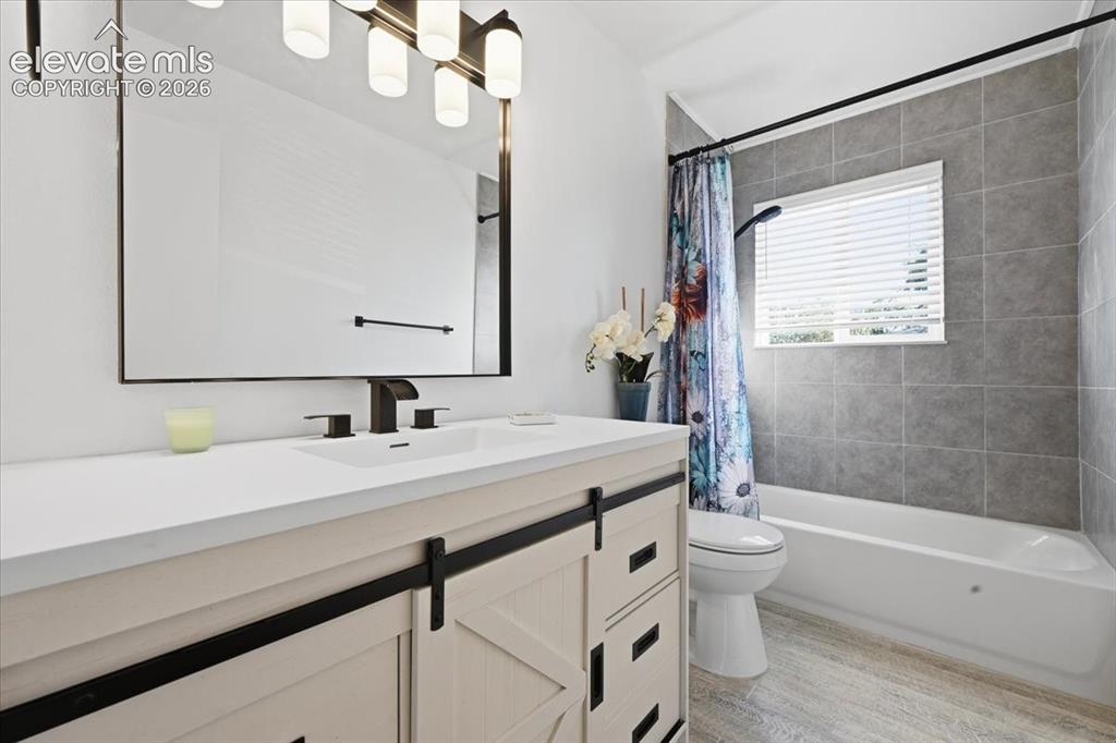 Image 14 of 27: Vanity with barn door style cabinetry, white countertop, and dark-finish fi