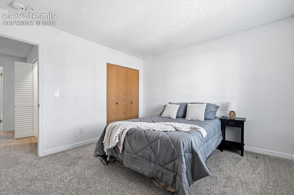 Image 16 of 27: White walls with textured ceilings, light-toned wood closet doors, and grey