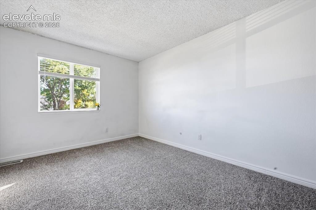 Image 17 of 27: Window with horizontal blinds, textured ceiling, light grey carpet, white w