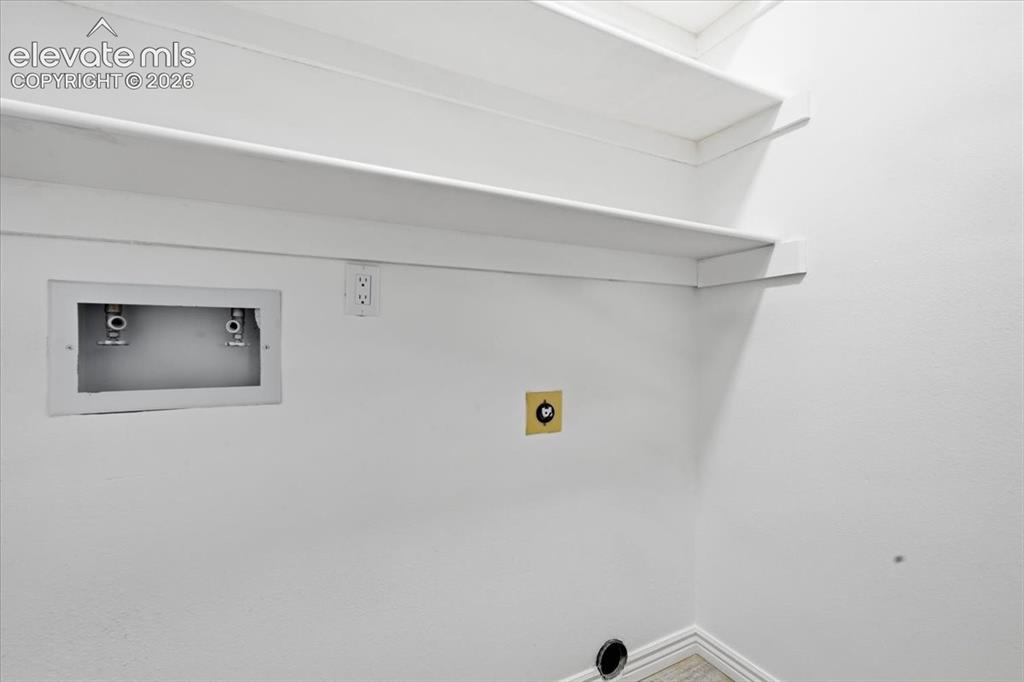 Image 20 of 27: Built-in shelving, white painted walls, water hookups, electrical outlet, a