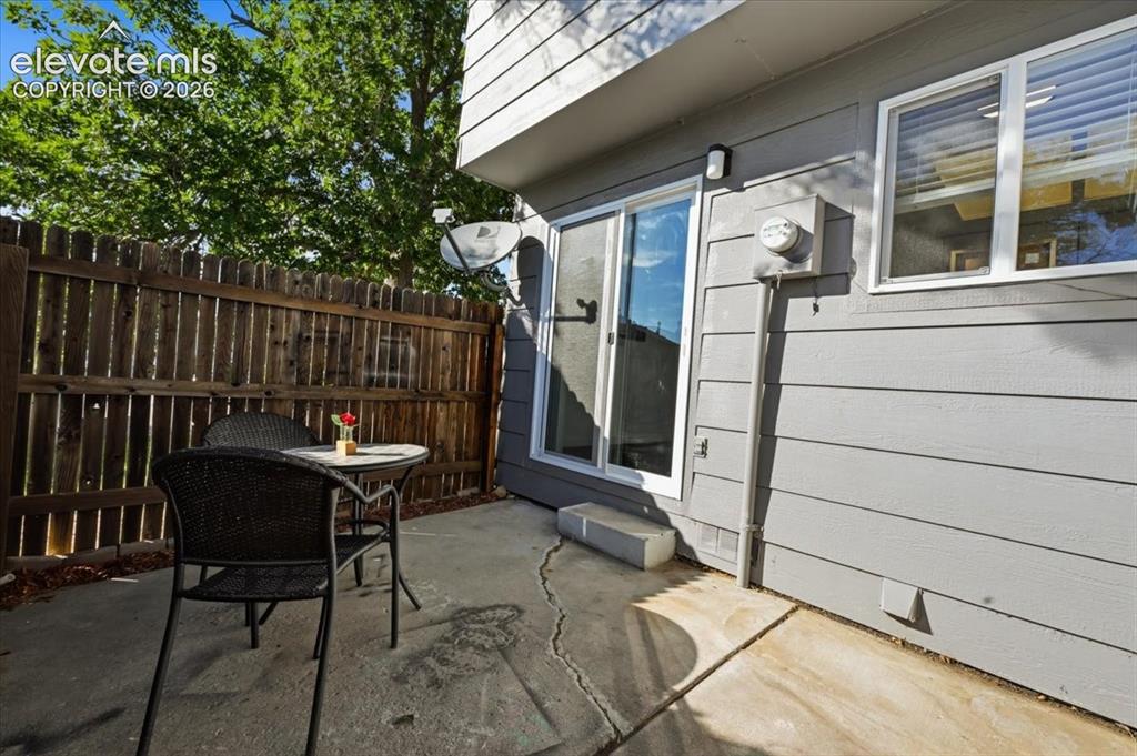 Image 21 of 27: Private concrete patio with a wood privacy fence and a sliding glass door