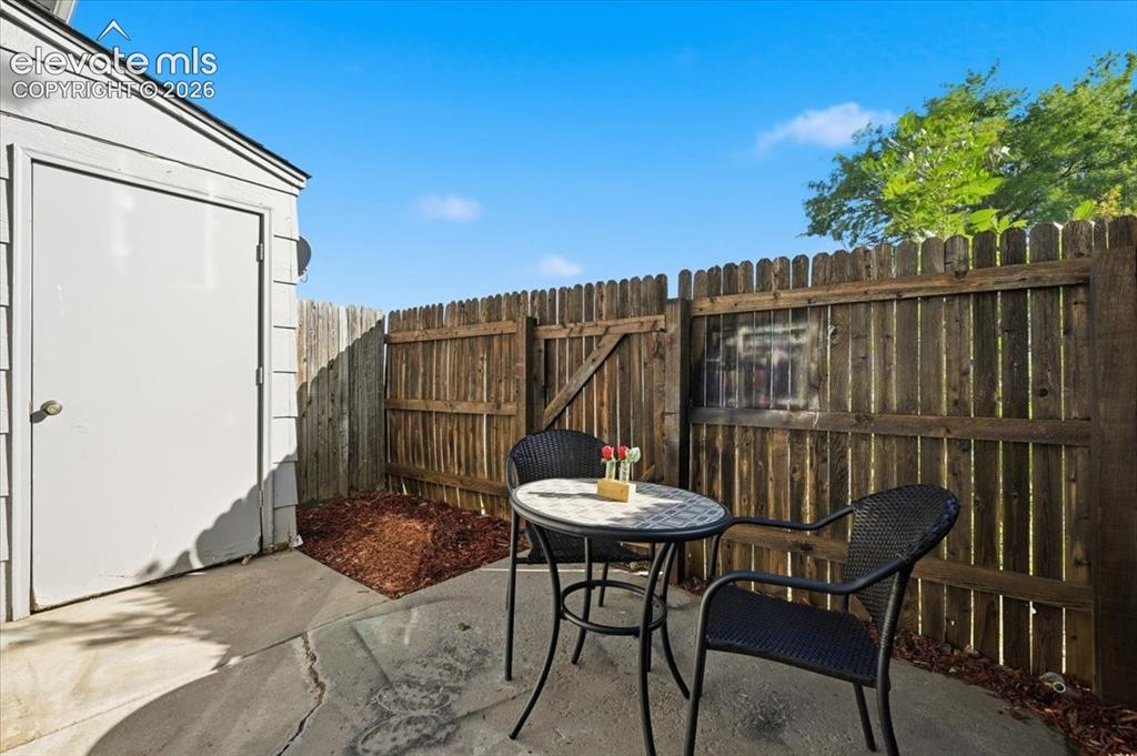 Image 22 of 27: Private patio area with concrete surfacing, enclosed by a wood privacy fenc