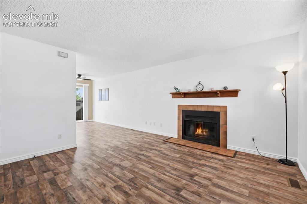 Image 4 of 27: Wood-finish flooring throughout, featuring a fireplace with a brick surroun