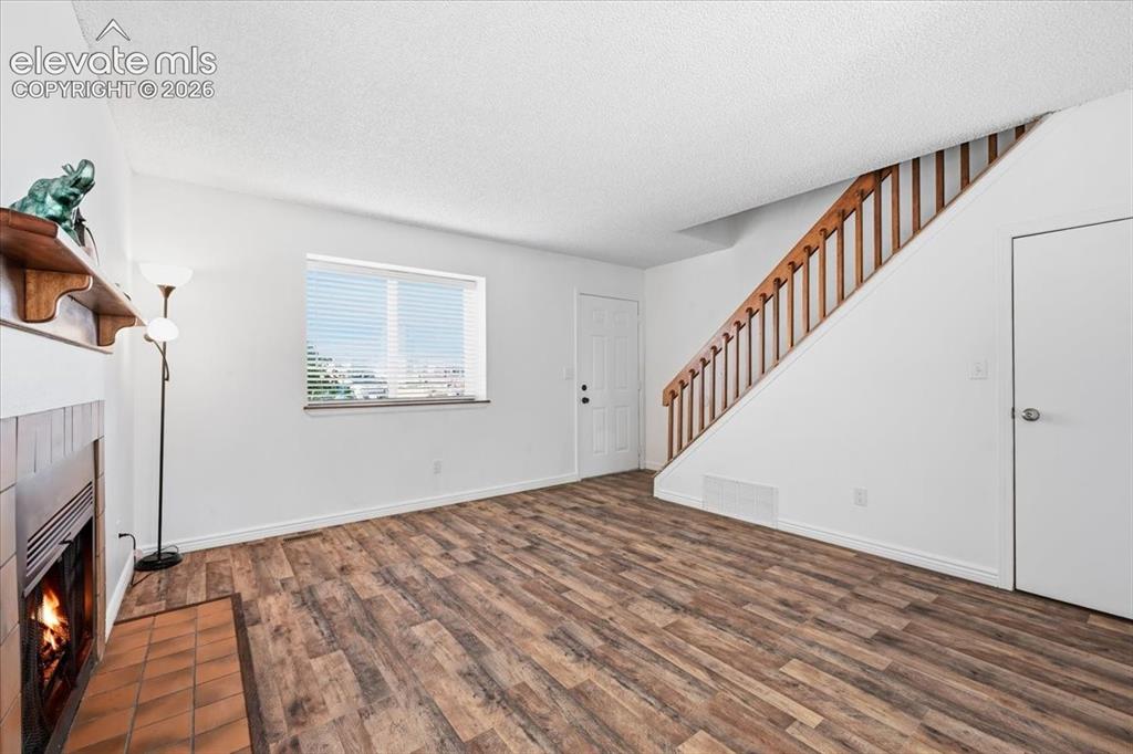 Image 5 of 27: Living space featuring wood-finish flooring, a fireplace with tile surround