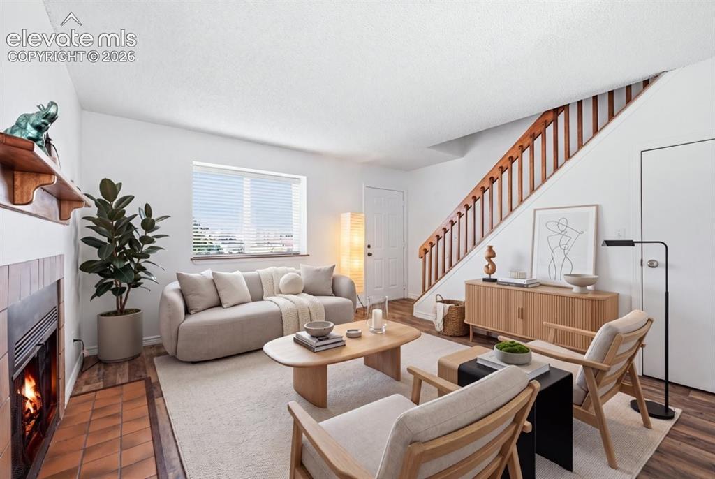 Image 6 of 27: Living area featuring wood-finish flooring, a fireplace with tile surround,