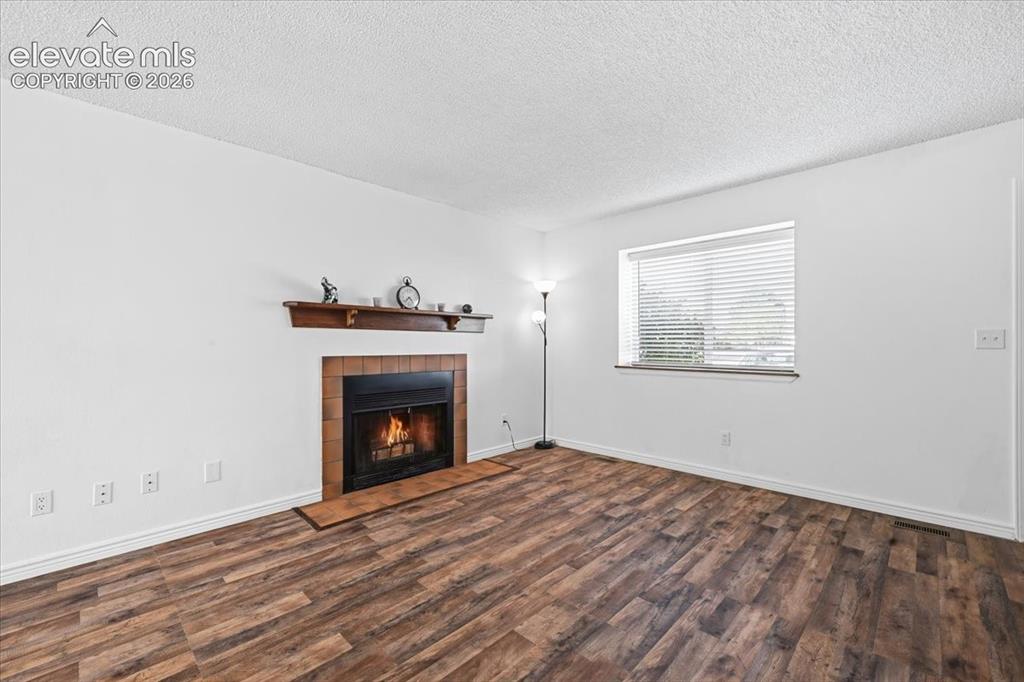 Image 7 of 27: Wood-finish flooring, brick-surround fireplace with a wood mantel, and wind