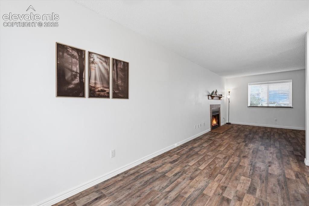 Image 8 of 27: Living area featuring wood-finish flooring, a built-in fireplace, a window 