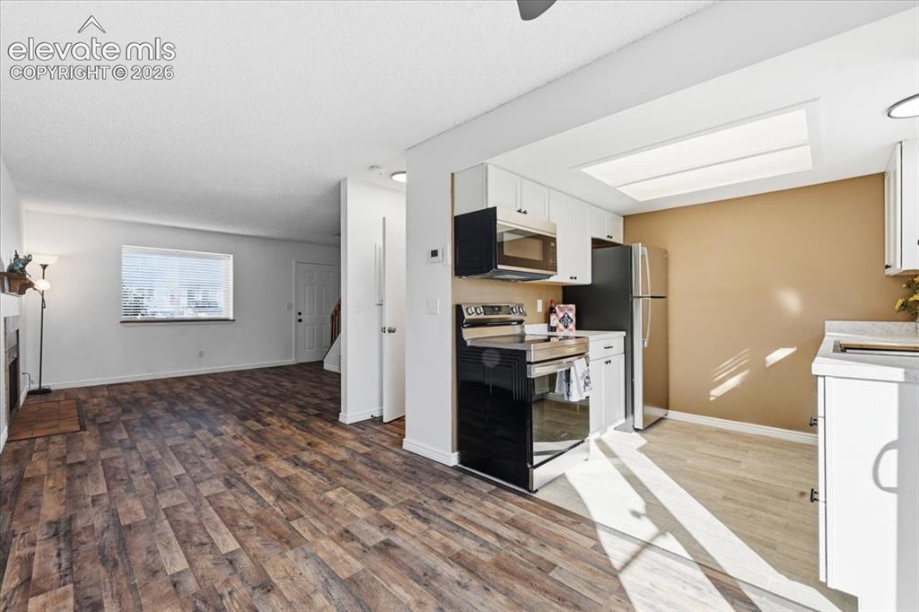 Image 9 of 27: Wood-finish flooring throughout, kitchen with white cabinetry, stainless st