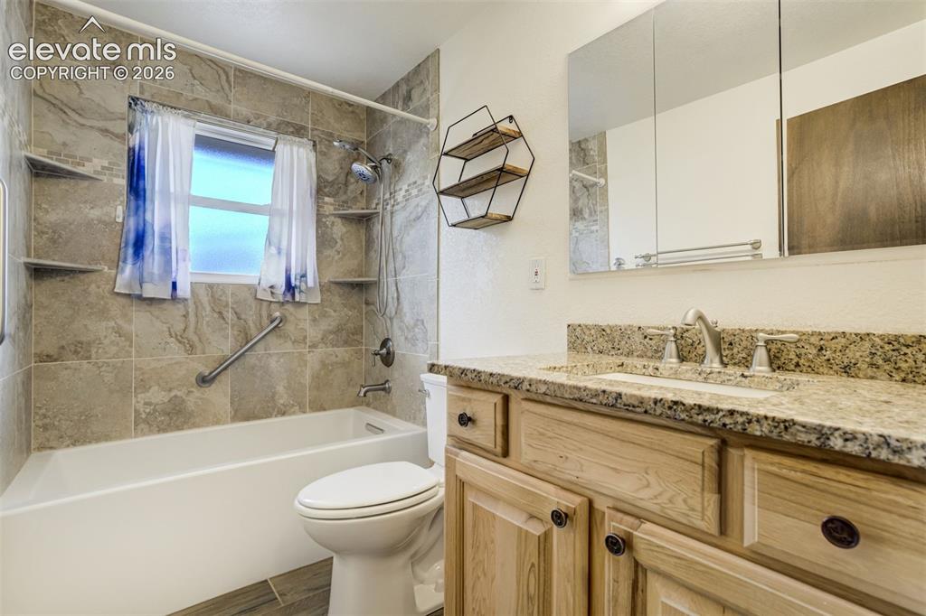 Image 29 of 50: Main level Full Bath with Custom Tile work, upgraded vanity with granite to