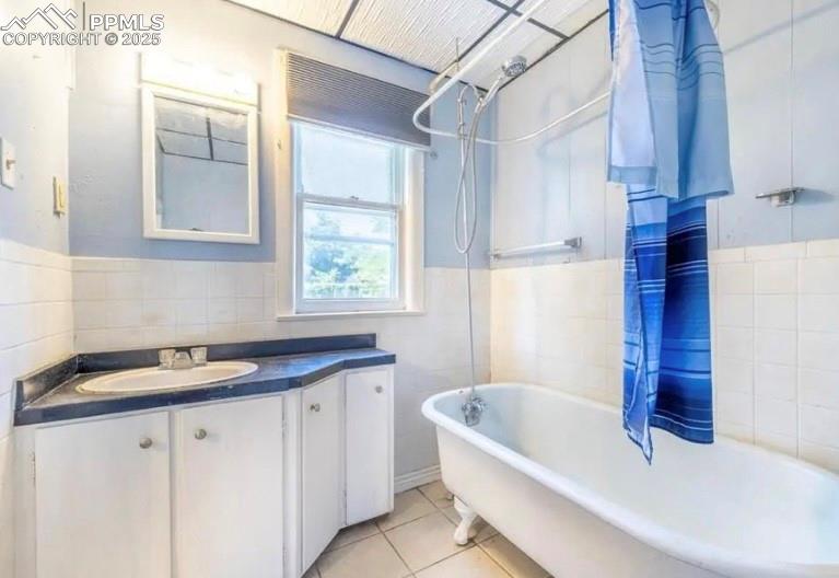 Image 9 of 9: Full bath with tile walls, a wainscoted wall, vanity, tile patterned floors