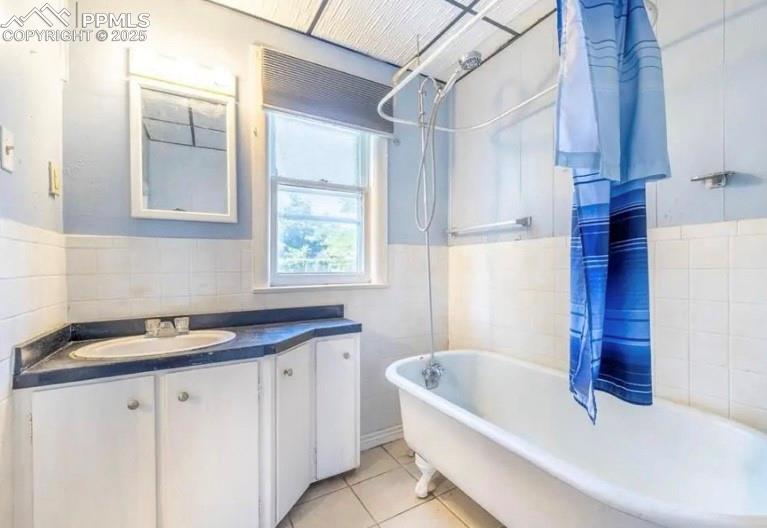 Image 9 of 9: Full bath with tile walls, a wainscoted wall, vanity, tile patterned floors