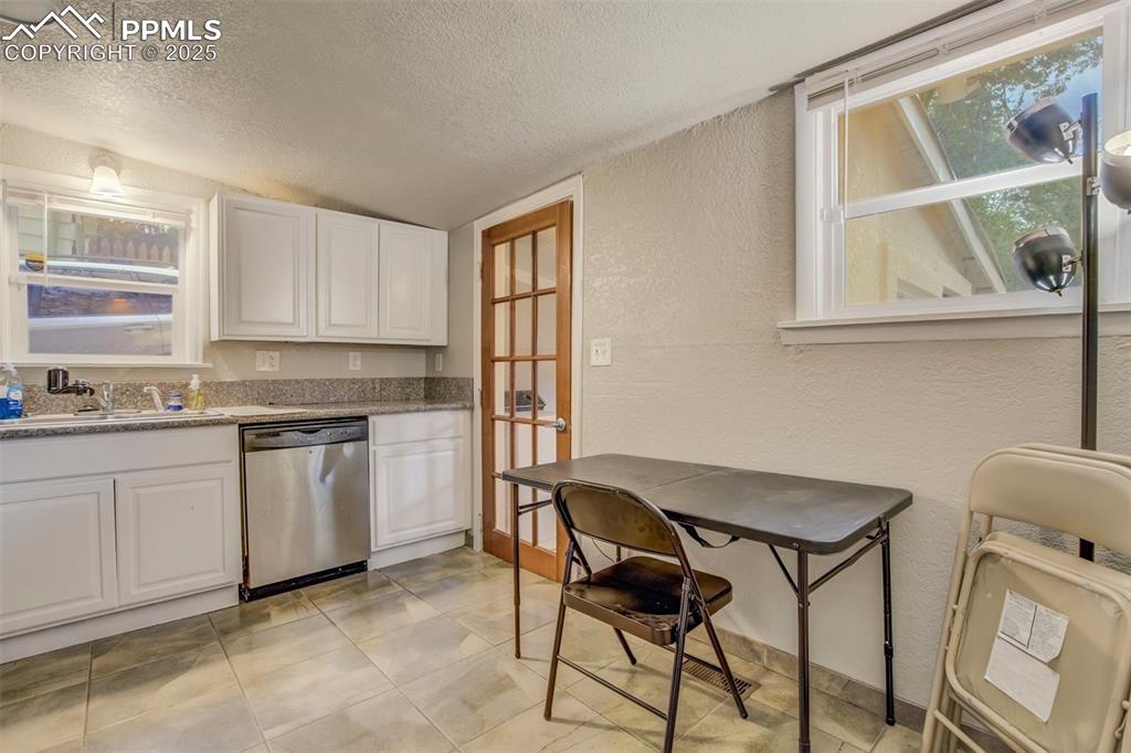 Image 11 of 24: Kitchen featuring stainless steel dishwasher, a textured wall, a textured c