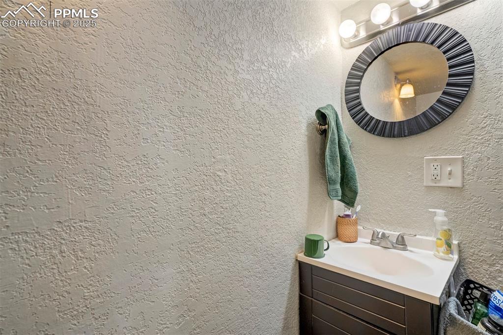 Image 18 of 24: Bathroom with a textured wall and vanity