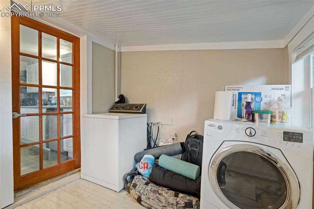 Image 21 of 24: Laundry area with washer and clothes dryer and light wood-type flooring