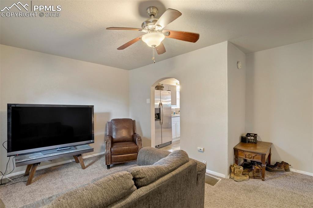 Image 5 of 24: Living room featuring arched walkways, a ceiling fan, and light carpet