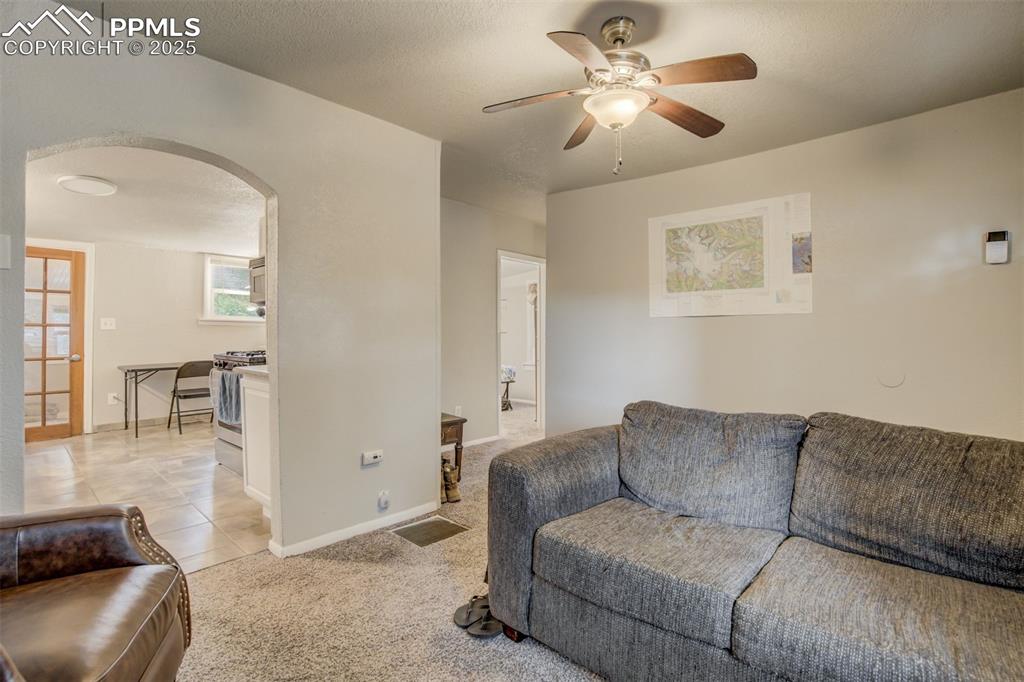 Image 6 of 24: Living area with arched walkways, a ceiling fan, and light tile patterned f