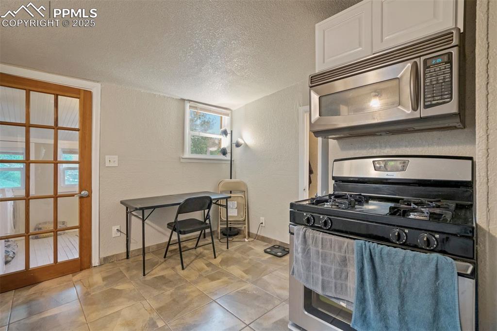 Image 7 of 24: Kitchen featuring stainless steel appliances, a textured ceiling, white cab